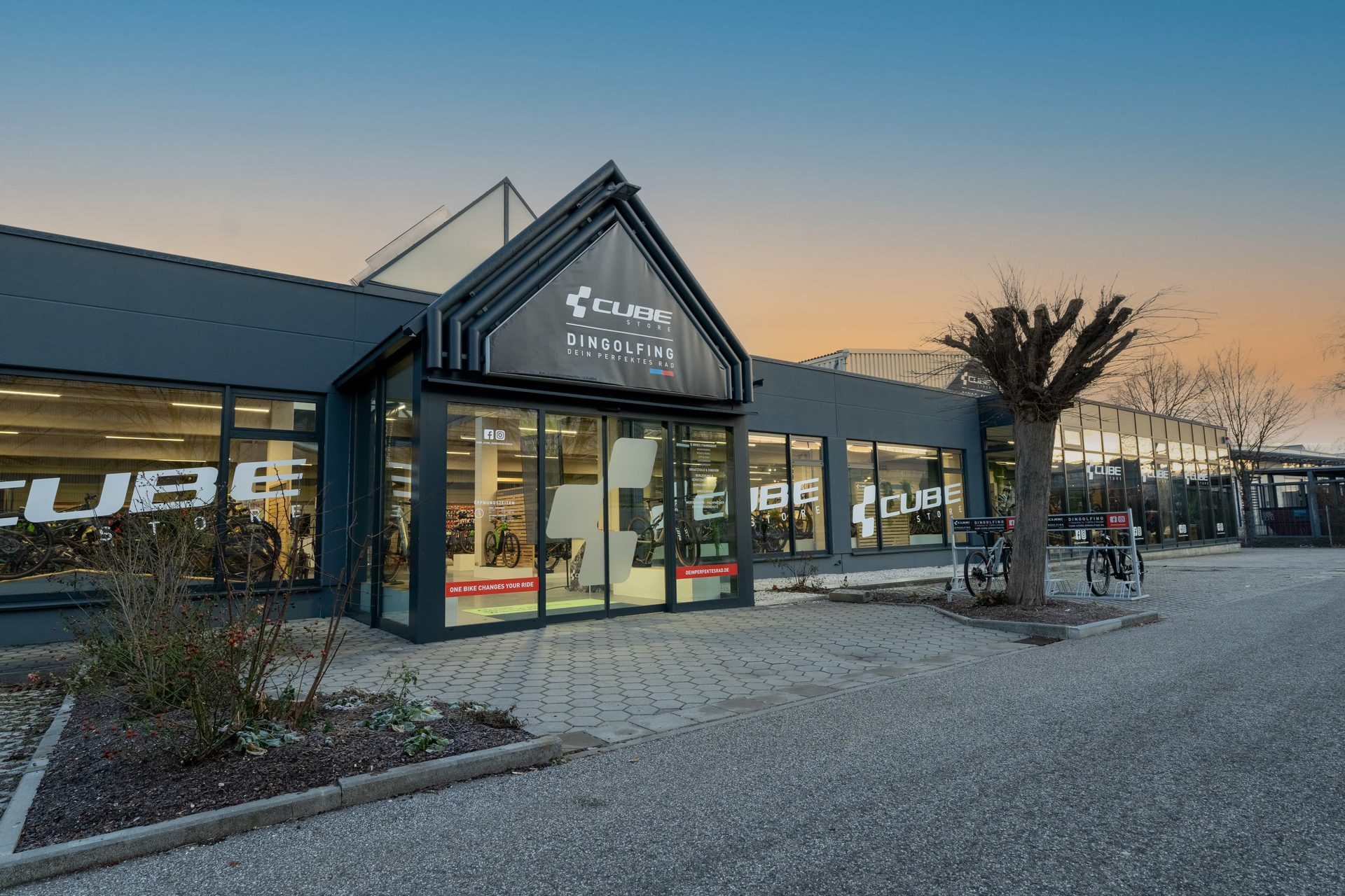 Eingang des CUBE Store Dingolfing in der Abenddämmerung