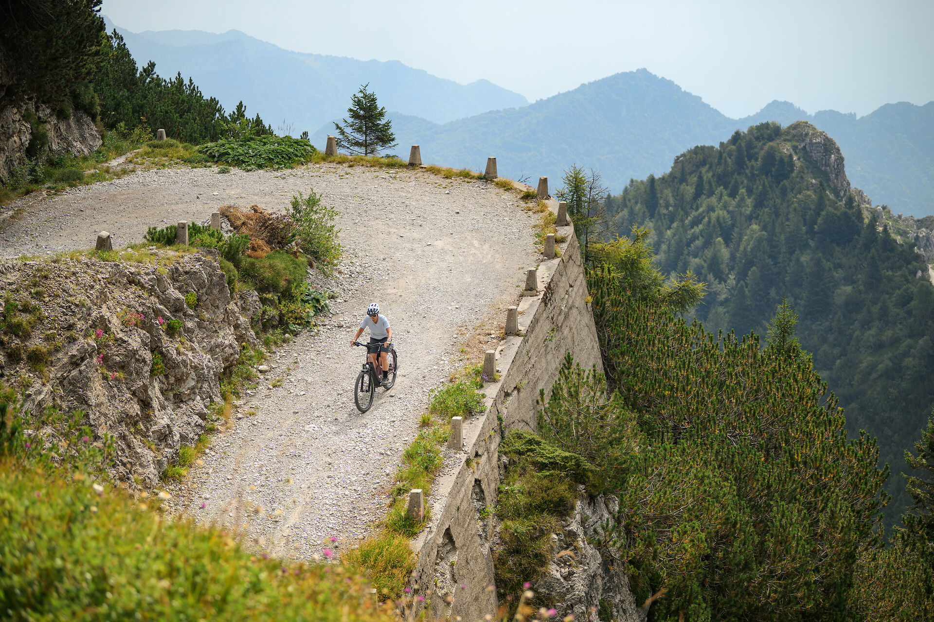 Fahrer auf einem E-Trekkingbike auf einer Schotterstraße am Berghang