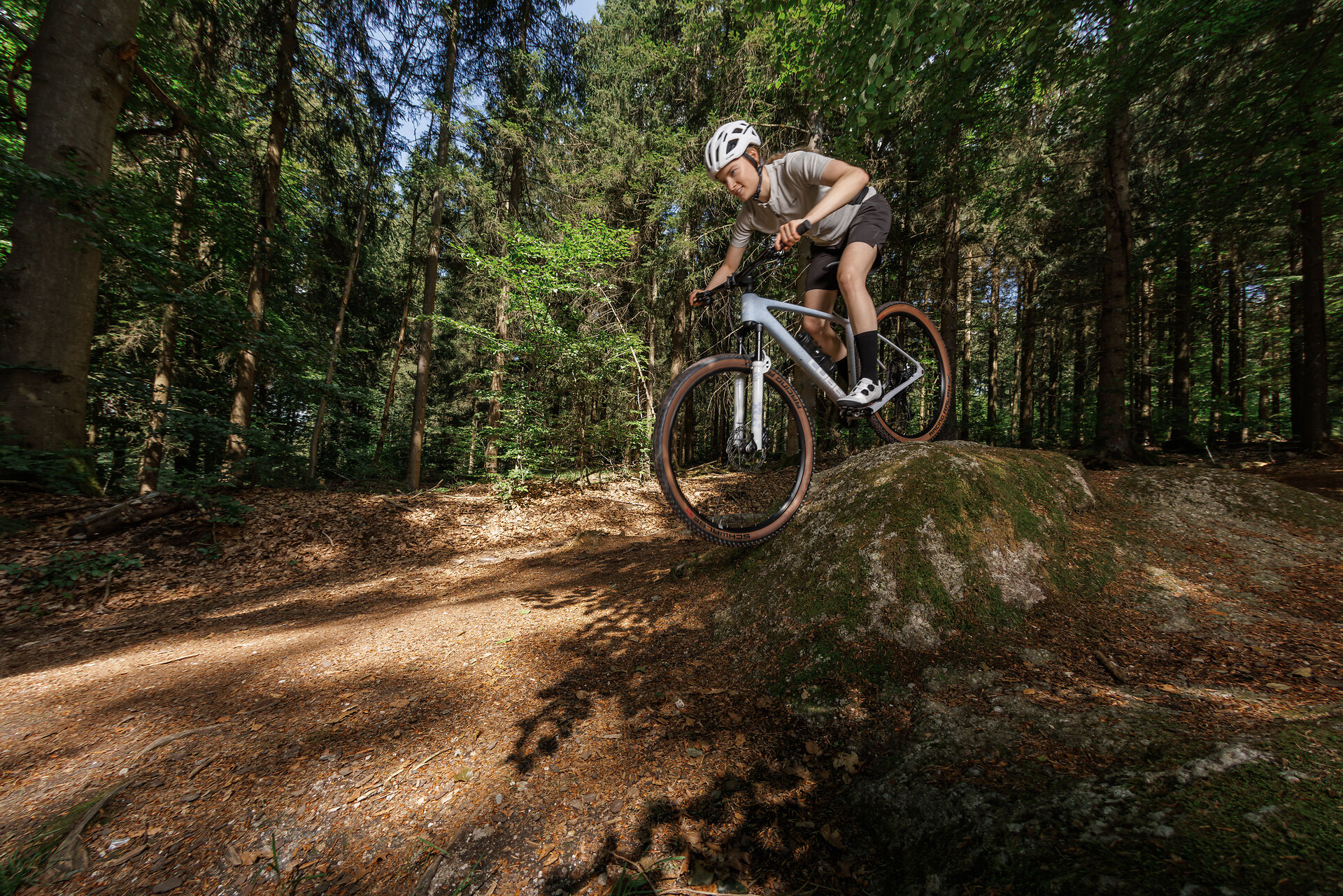 Mountainbiker springt mit einem Hardtail über eine Waldkuppe