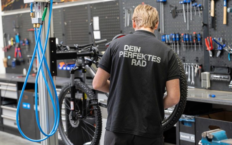 Mechaniker arbeitet an einem Mountainbike im Montageständer der Werkstatt