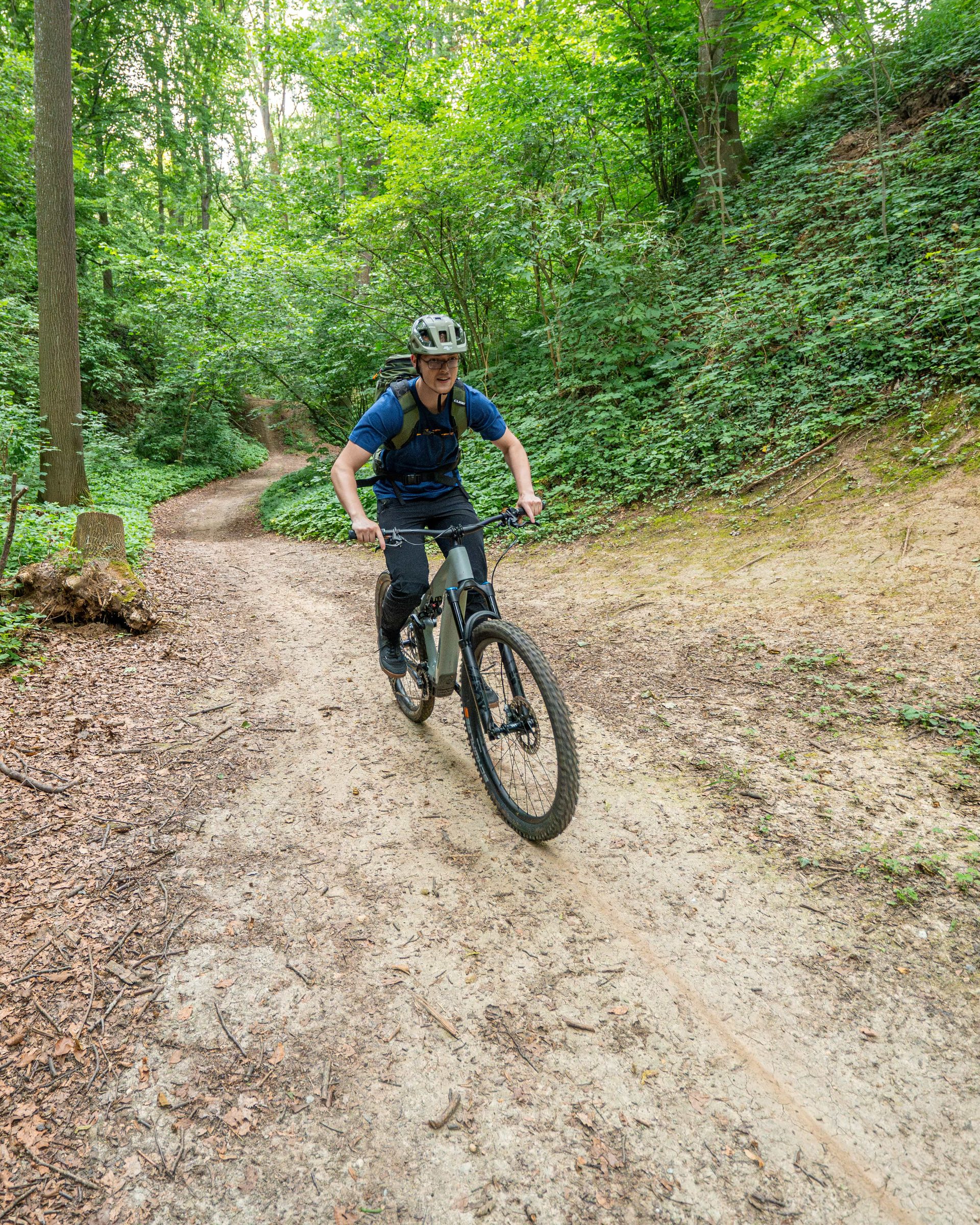 E-Mountainbiker fährt auf einem Waldtrail bei Dingolfing auf die Kamera zu